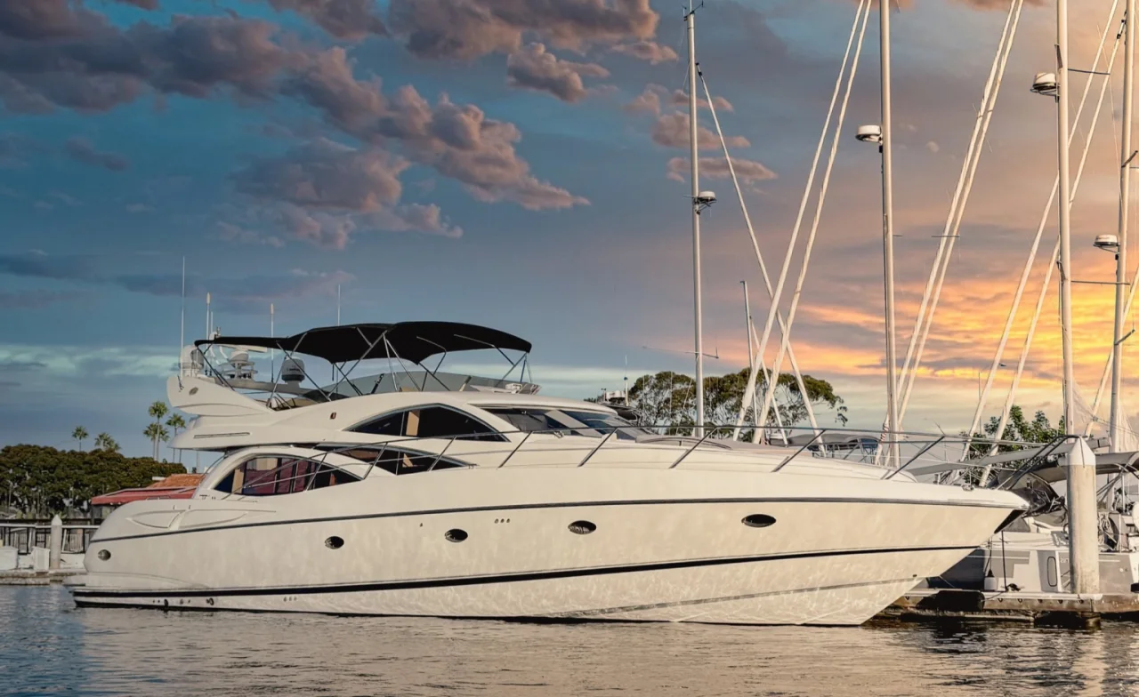 White Sunseeker yacht moored beside sailboats at sunset